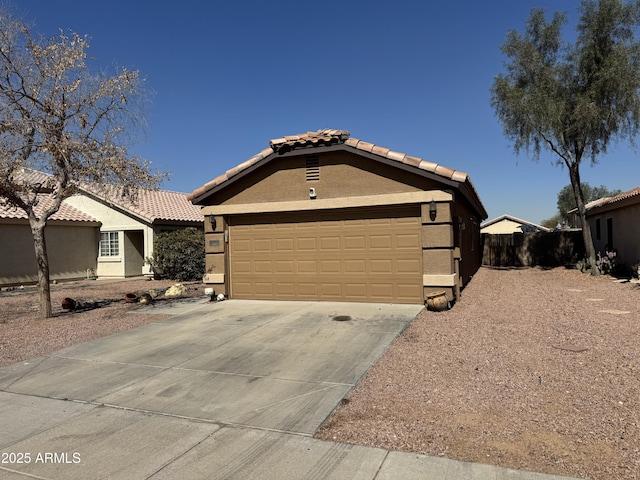 view of front of property featuring fence, driveway, an attached garage, stucco siding, and a tiled roof