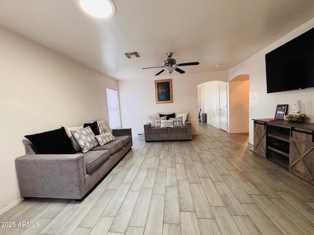 living area featuring wood finish floors, visible vents, arched walkways, and a ceiling fan