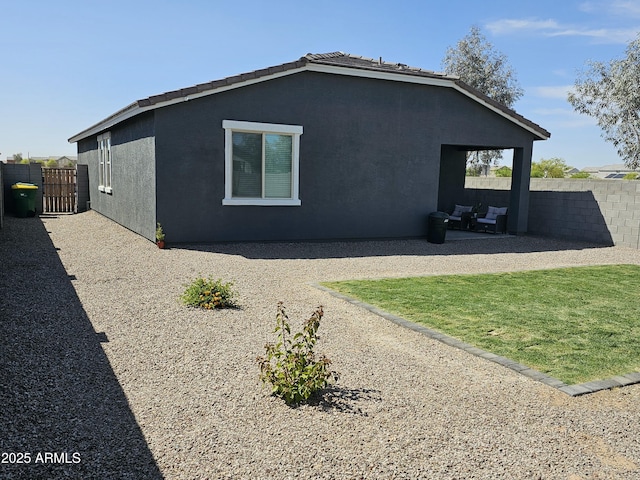 view of side of property with a tile roof, fence, a patio, and stucco siding