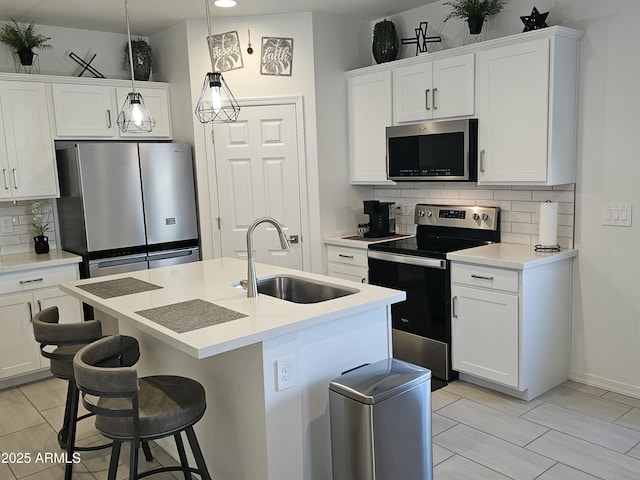 kitchen with a center island with sink, a sink, white cabinetry, and stainless steel appliances