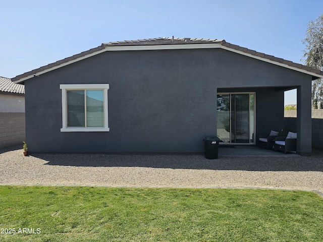 back of house featuring a yard, a patio area, stucco siding, and a tiled roof