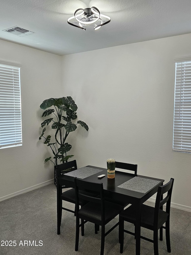 carpeted dining space featuring visible vents, baseboards, and a textured ceiling