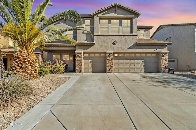 view of front facade with a garage, stone siding, concrete driveway, and stucco siding