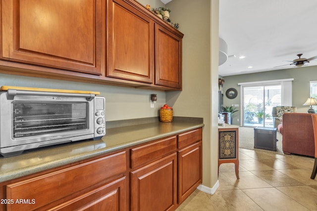 kitchen featuring arched walkways, a toaster, light tile patterned floors, brown cabinetry, and open floor plan