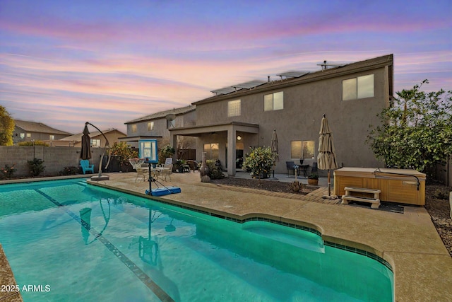 pool at dusk with a patio area, a fenced backyard, a fenced in pool, and a hot tub