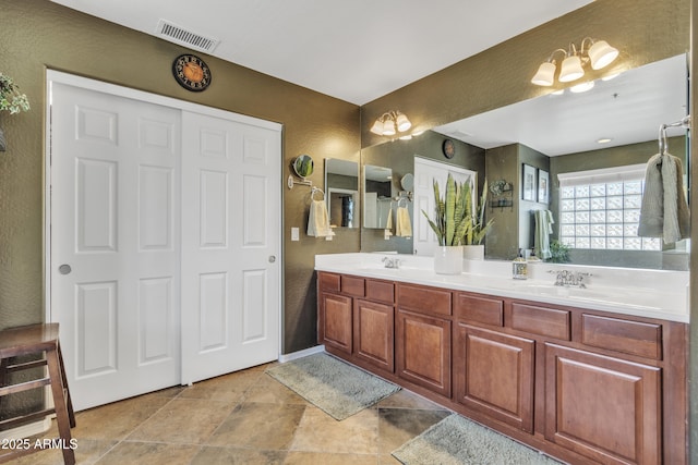 full bath featuring double vanity, a sink, and visible vents