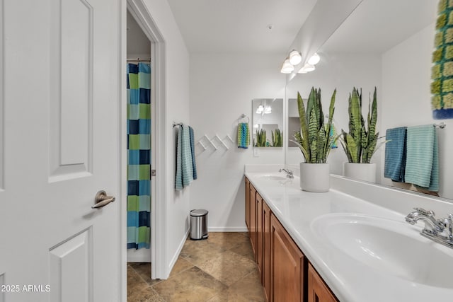 full bathroom featuring a sink, baseboards, and double vanity