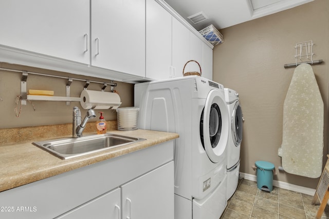 washroom with washing machine and dryer, a sink, visible vents, baseboards, and cabinet space