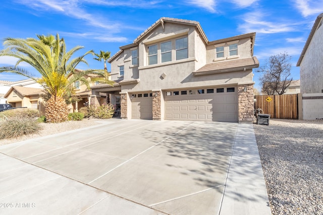 view of front of home with an attached garage, fence, stone siding, driveway, and stucco siding