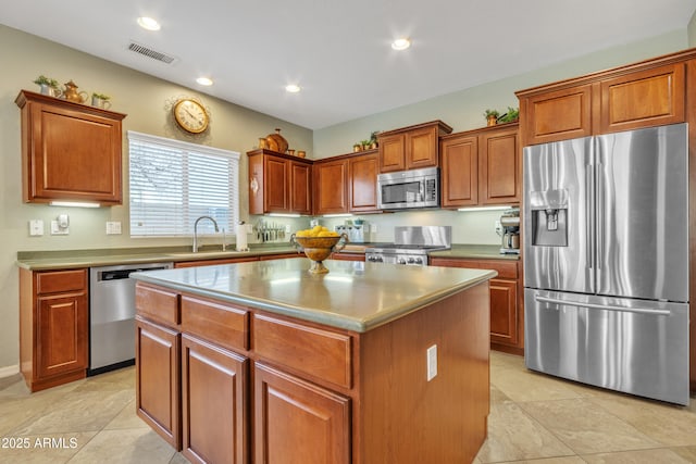 kitchen with visible vents, brown cabinetry, a kitchen island, stainless steel appliances, and a sink