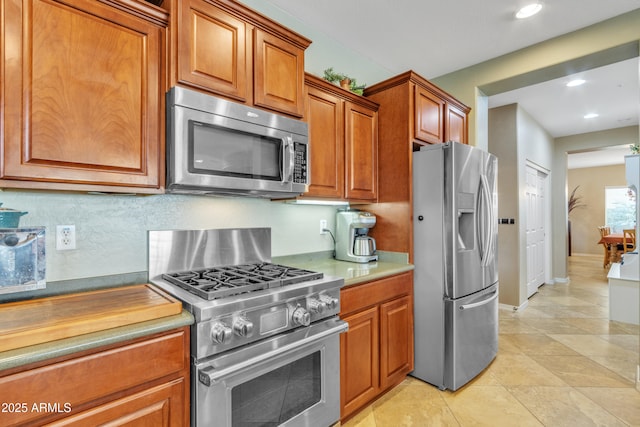 kitchen featuring brown cabinets, stainless steel appliances, recessed lighting, tasteful backsplash, and light countertops