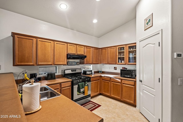 18057 W Port Royale Ln, Surprise, AZ 85388 - kitchen featuring under cabinet range hood, black microwave, brown cabinetry, and stainless steel gas range