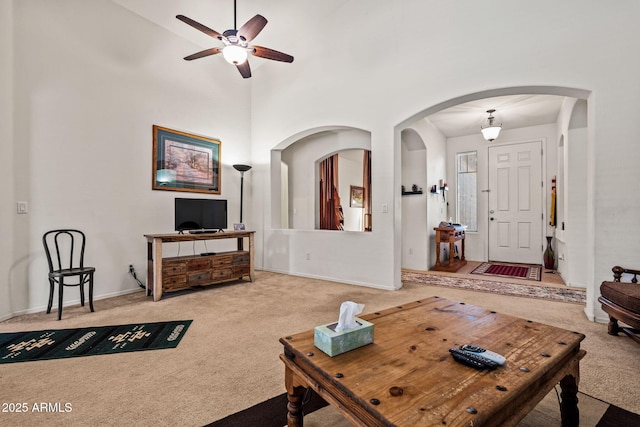 18057 W Port Royale Ln, Surprise, AZ 85388 - carpeted living area featuring arched walkways, a towering ceiling, and a ceiling fan