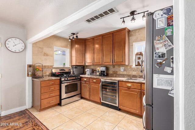 kitchen featuring stainless steel appliances, track lighting, beverage cooler, and backsplash