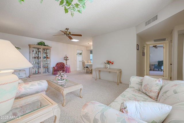 carpeted living room with ceiling fan and a textured ceiling