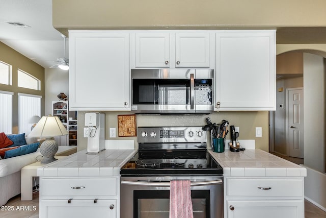 kitchen featuring tile counters, stainless steel appliances, and white cabinets