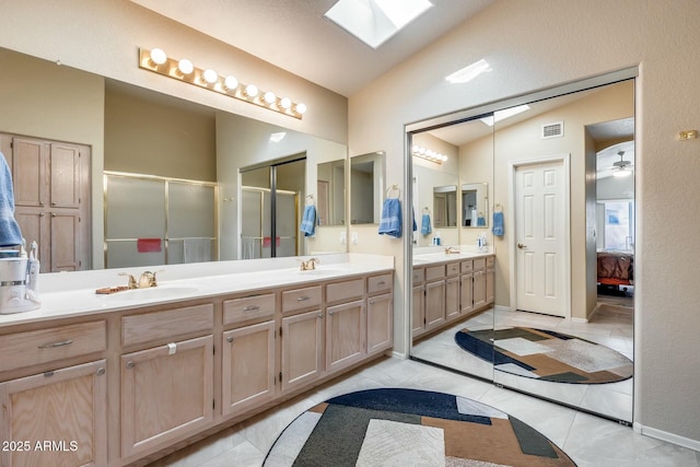 bathroom with tile patterned flooring, vanity, vaulted ceiling with skylight, and an enclosed shower