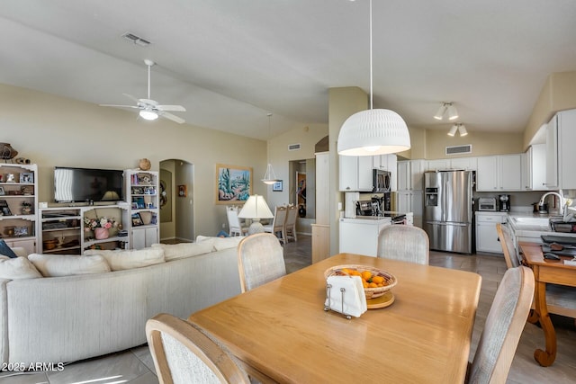 dining area featuring ceiling fan, sink, vaulted ceiling, and light tile patterned floors