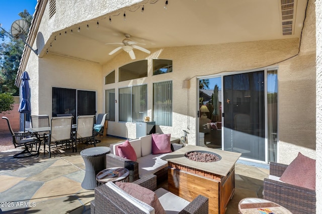 view of patio with ceiling fan and an outdoor living space with a fire pit