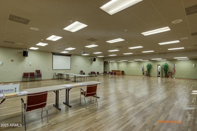 interior space featuring a drop ceiling, light hardwood / wood-style floors, and a kitchen bar