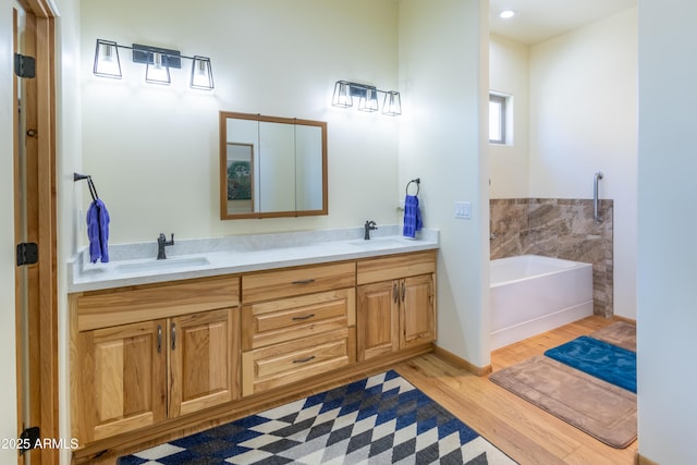 bathroom with a bath, vanity, and hardwood / wood-style flooring