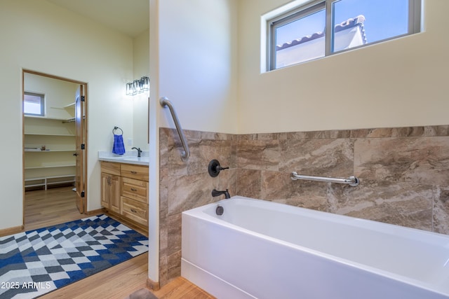 bathroom with hardwood / wood-style flooring, vanity, and a washtub