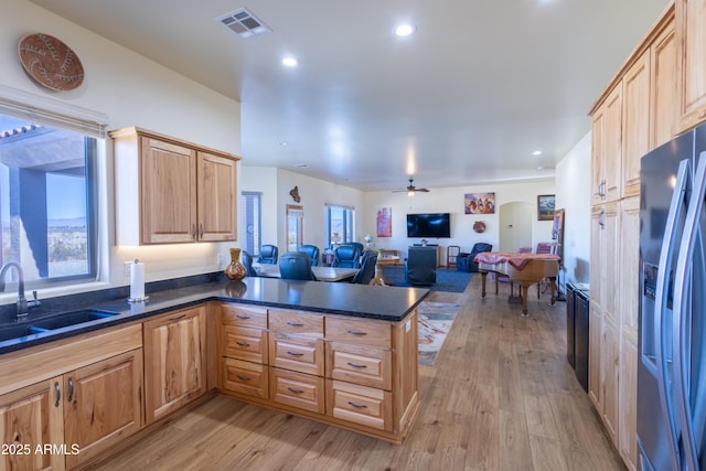 kitchen with kitchen peninsula, light wood-type flooring, ceiling fan, sink, and stainless steel fridge with ice dispenser