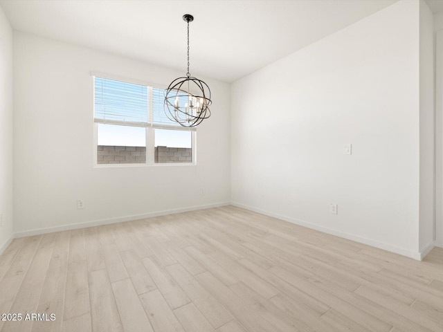 empty room featuring light wood-style flooring, a notable chandelier, and baseboards