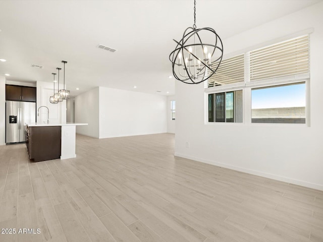 unfurnished living room with a chandelier, light wood-style floors, visible vents, and recessed lighting