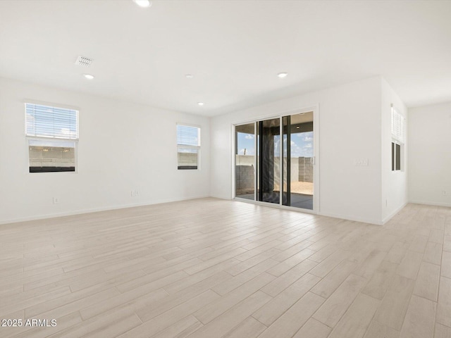 empty room with a wealth of natural light, light wood finished floors, and recessed lighting