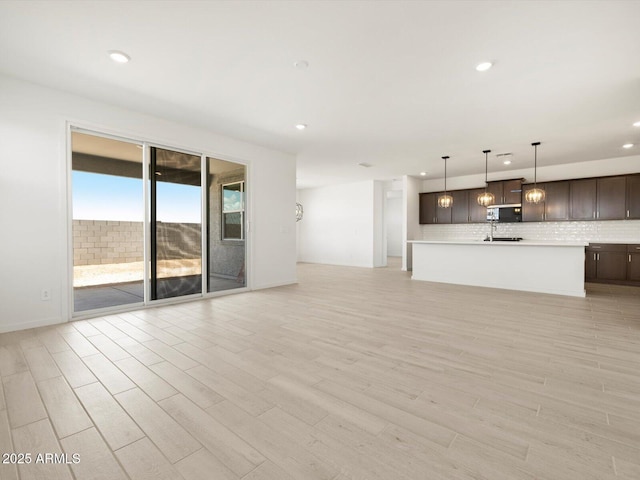 unfurnished living room with a sink, light wood-style flooring, and recessed lighting