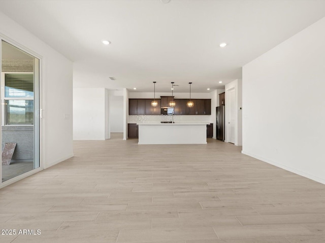 unfurnished living room with recessed lighting, light wood finished floors, and baseboards