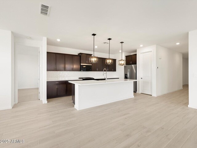 kitchen with light countertops, visible vents, black microwave, and dark brown cabinetry