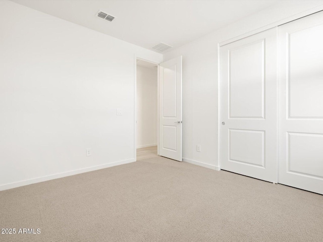 unfurnished bedroom with visible vents, baseboards, a closet, and light carpet