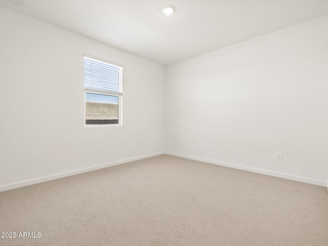 empty room featuring light colored carpet and baseboards