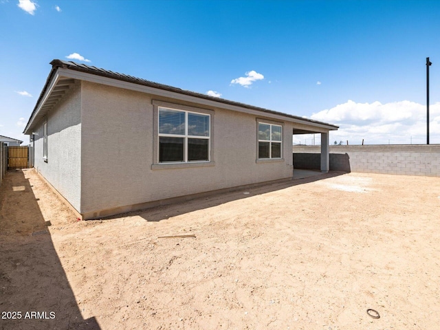 rear view of house featuring stucco siding and a fenced backyard