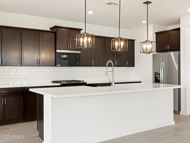 kitchen featuring stainless steel fridge with ice dispenser, visible vents, an inviting chandelier, light wood-type flooring, and dark brown cabinets
