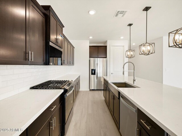 kitchen with visible vents, an inviting chandelier, a sink, light countertops, and stainless steel appliances