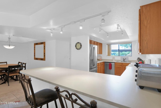 8651 E Royal Palm Rd Unit 121, Scottsdale, AZ 85258 - kitchen featuring stainless steel appliances, a peninsula, a breakfast bar area, light countertops, and brown cabinetry