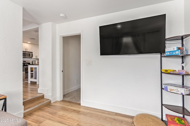 interior space featuring baseboards, wood finished floors, and appliances with stainless steel finishes