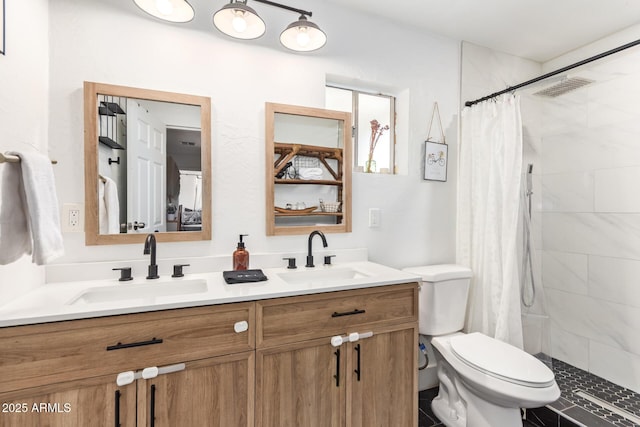 bathroom featuring double vanity, a sink, toilet, and tiled shower