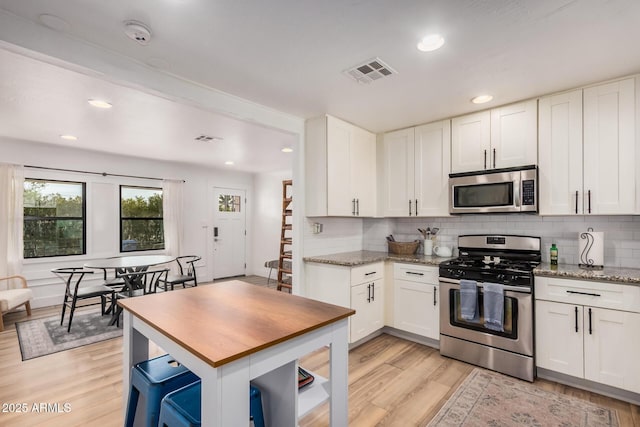 kitchen featuring white cabinets, light wood-style flooring, appliances with stainless steel finishes, and visible vents