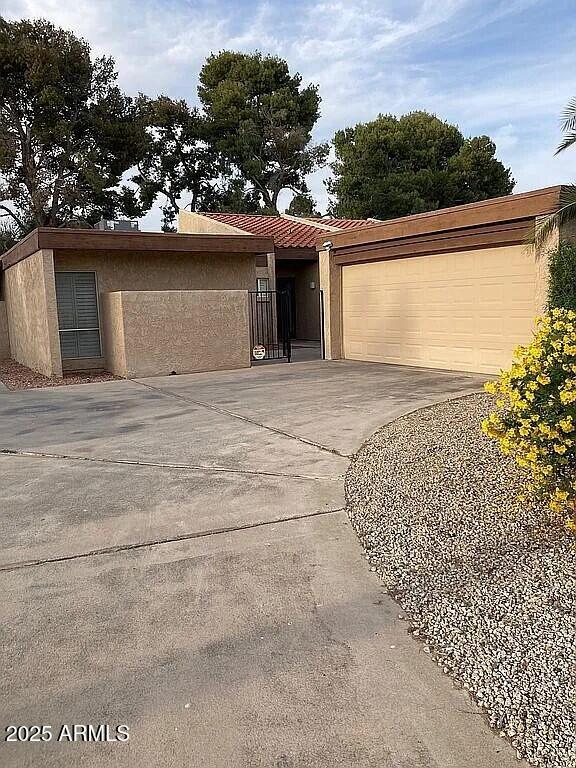 single story home featuring a garage, concrete driveway, and stucco siding