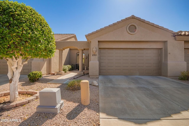 view of front of home with driveway, an attached garage, a tile roof, and stucco siding