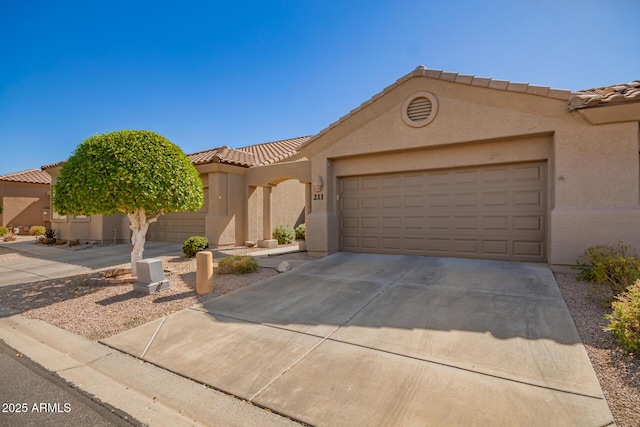 view of front of property with a garage, driveway, a tiled roof, and stucco siding