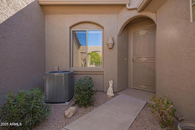 property entrance featuring cooling unit and stucco siding