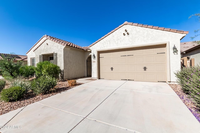 mediterranean / spanish house with driveway, a tile roof, a garage, and stucco siding