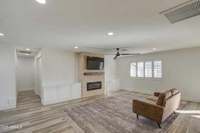 living room featuring a brick fireplace, ceiling fan, and light hardwood / wood-style flooring