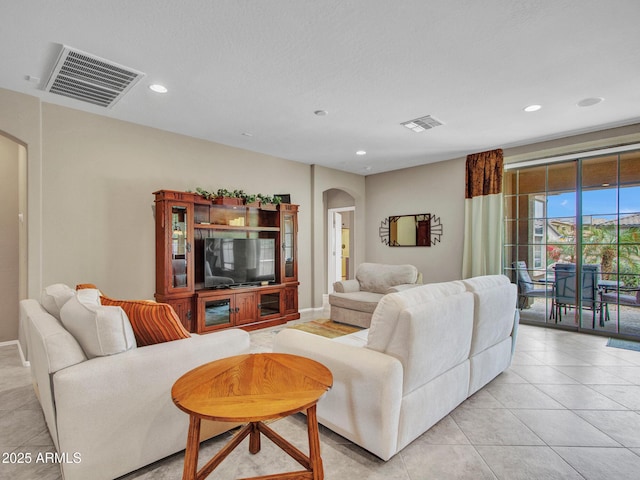 living area featuring visible vents, light tile patterned flooring, and arched walkways