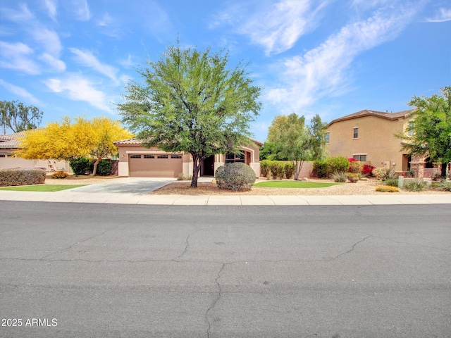 obstructed view of property featuring concrete driveway, stucco siding, a garage, and fence
